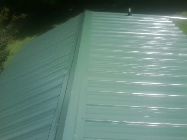 New green metal panels meeting at the ridge of a roof — Flat Roof Repair work by our crew in Oakley