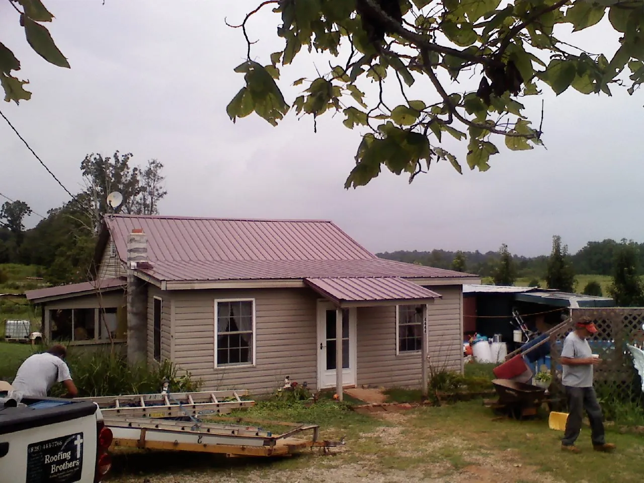 Crew finishing a mauve metal roof on a small farmhouse in Oakley