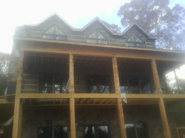 Dormers and porch framing on a large log home under construction — Roof Coating work by our crew in Oakley