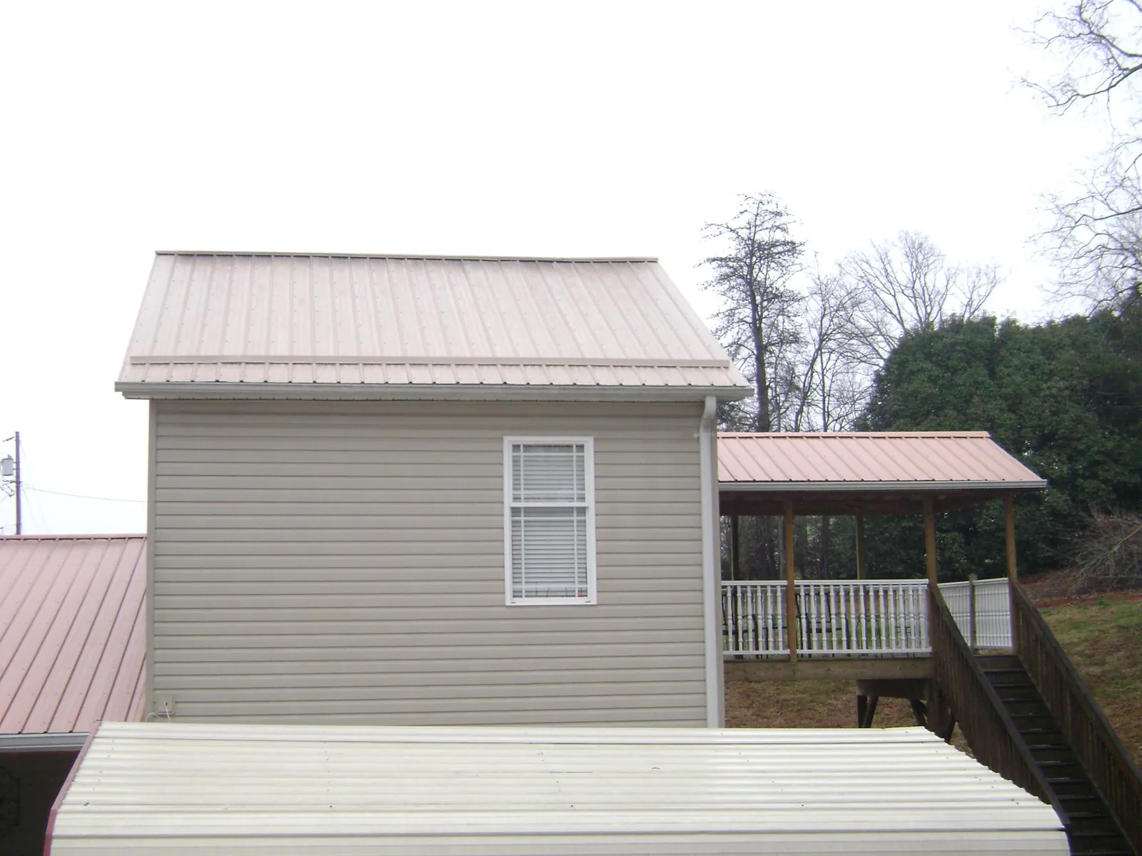 Tan metal roofs on a two story addition and attached porch, from a Roof Replacement job in Oakley